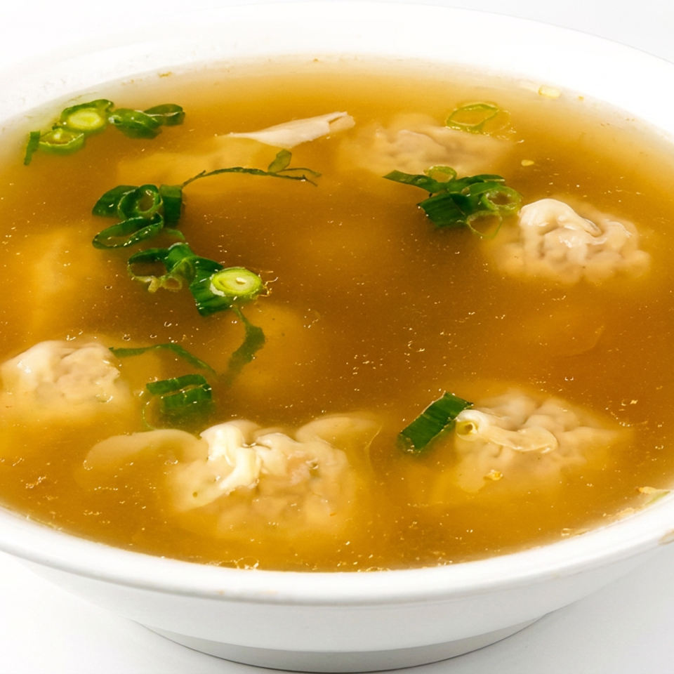 Bowl of clear broth soup with dumplings and sliced green onions.