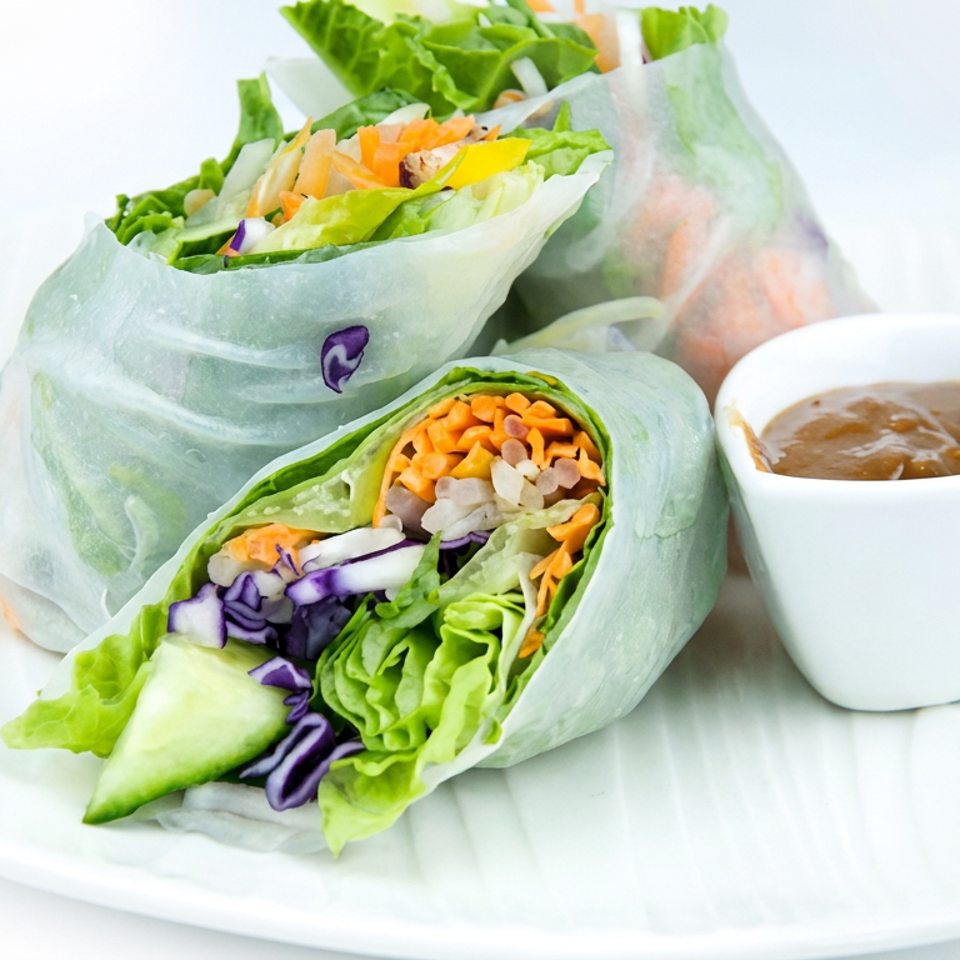 Fresh vegetable spring rolls filled with lettuce, carrots, cabbage, cucumber, and rice noodles, served with dipping sauce.